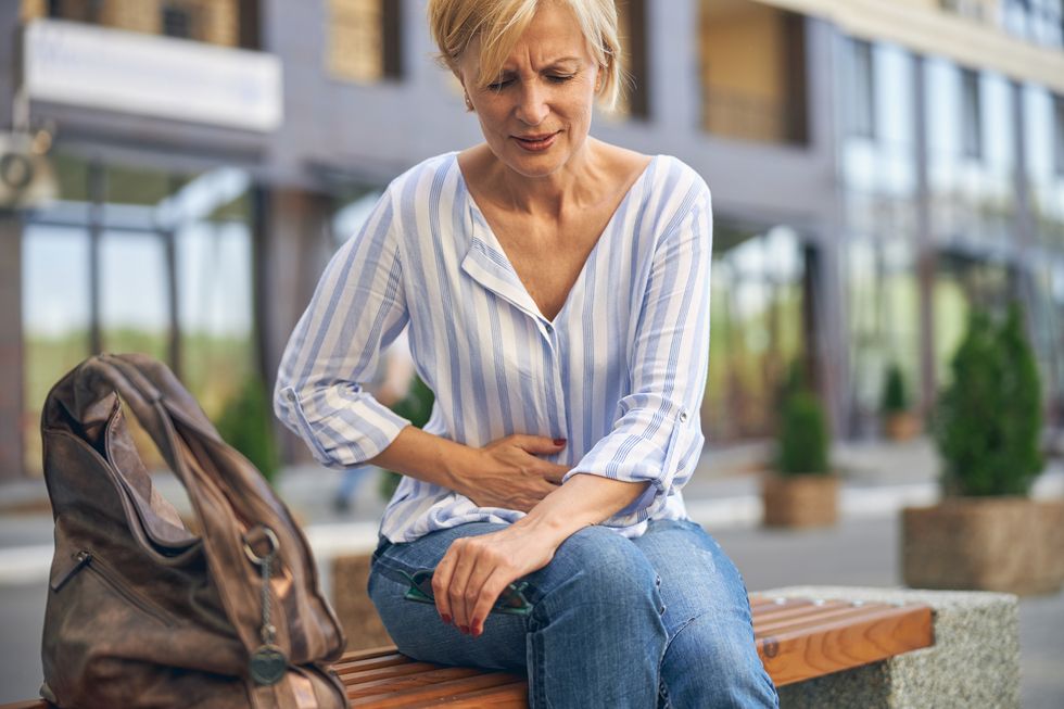 Sitting woman holding her hurting tummy