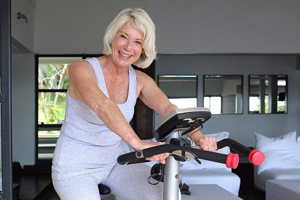 Mature woman is doing exercise on home trainer