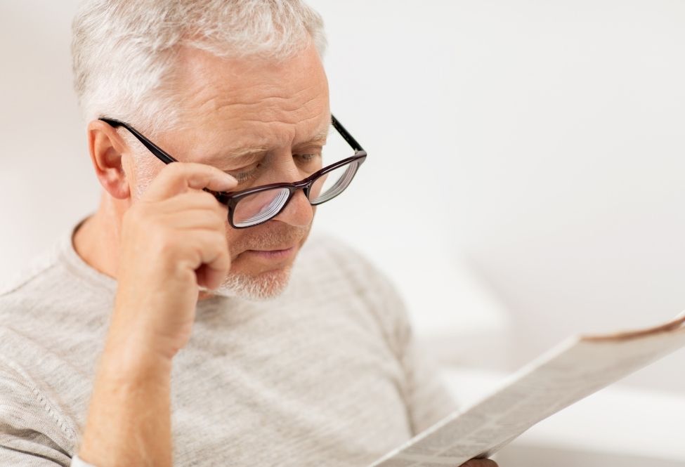 older man with glasses, reading newspaper