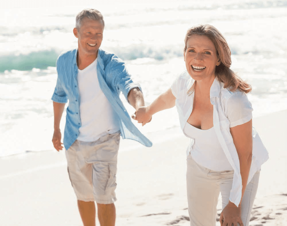 man and woman running ont he beach while holding hands