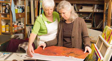 two elderly woman looking at a dyed paper